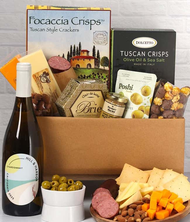A charcuterie gift set with Tuscan crisps, focaccia crackers, 3 cheeses, olives, mustard, sausage almonds, chocolate-covered popcorn and a bottle of California Chardonnay.