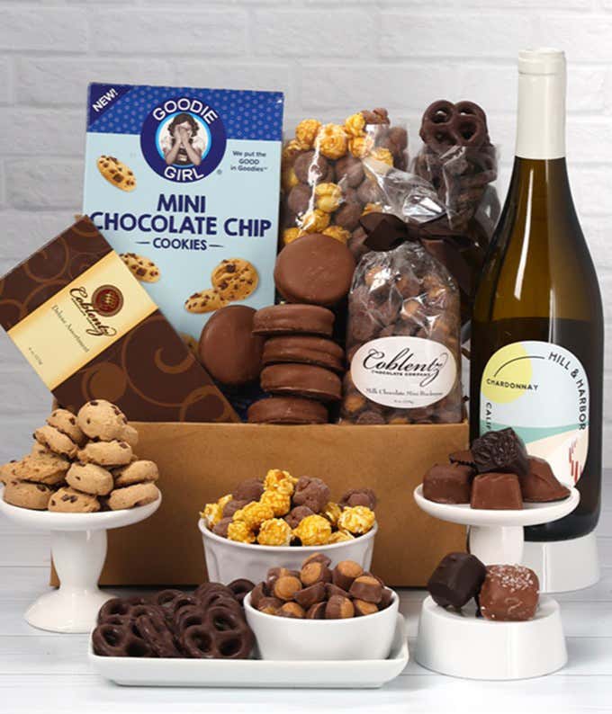 A gift set featuring a bottle of Hill & Harbor White Wine alongside chocolate-covered pretzels, mini cookies, caramel popcorn, chocolate-covered almonds, and 6 chocolate-covered Oreos. Includes a box of assorted chocolates for a luxurious touch.
