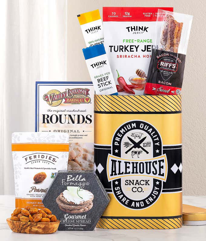This Alehouse-themed gift tin features a sleek black and yellow design filled with gourmet snacks. It includes Think Jerky's Turkey Jerky and Beef Sticks, Riffs Bacon, Valley Lahvosh crackers, Feridies Peanuts, and Bella Formaggio Cheese Spread. ?&#