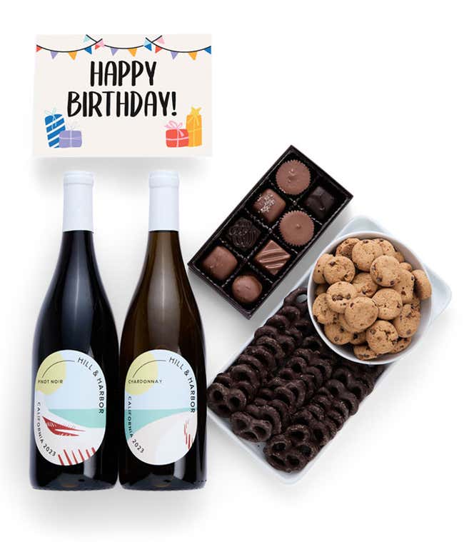 A birthday gift set with two bottles of Hill &amp; Harbor wine (Pinot Noir and Chardonnay), a box of assorted chocolates, a tray of chocolate-covered pretzels, a bowl of mini chocolate chip cookies, and a birthday message card.