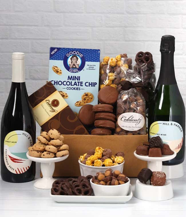 A gift set with 2 bottles of wine - red and sparkling, paired with chocolate pretzels, caramel popcorn, mini cookies, chocolate peanut butter buckeyes, six chocolate-covered Oreos, and a box assorted chocolates.