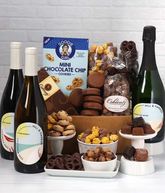 A gift set with 3 bottles of wine - red, white and sparkling, paired with chocolate pretzels, caramel popcorn, mini cookies, chocolate peanut butter buckeyes, six chocolate-covered Oreos, and a box assorted chocolates.